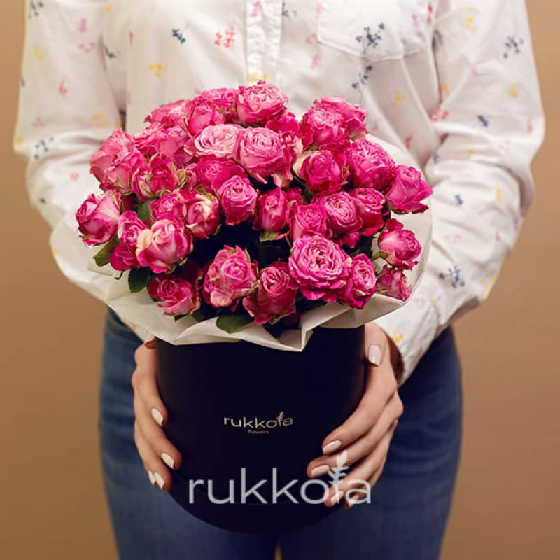 Розовые кустовые розы в средней черной шляпной коробке